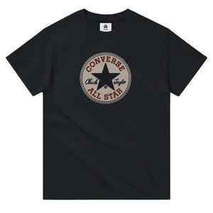 Puede incluir: Camiseta negra con un logotipo vintage de Converse All Star con una estrella roja y el texto "Converse Chuck Taylor All Star".