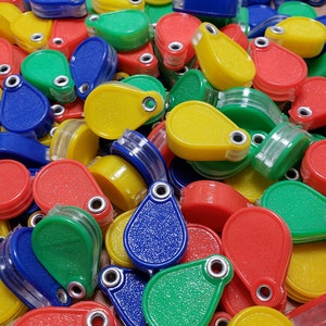 May include: A pile of colorful magnifying glasses in red, yellow, blue, and green. The magnifying glasses are teardrop shaped and have a clear plastic lens.