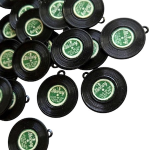 May include: A collection of small, black, circular ornaments resembling miniature vinyl records. Each ornament features a green and white label with the word "Mercury" and the text "Love Me or Leave Me Patti Page."