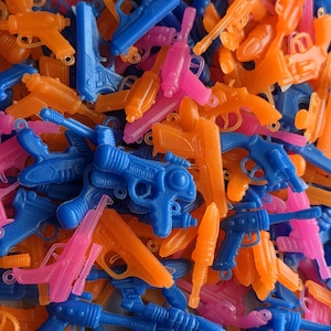 May include: A collection of colorful toy water guns in shades of blue, orange, and pink. The plastic guns are of various sizes and designs, creating a playful and vibrant assortment.