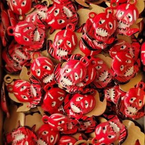 May include: A large group of red and black skull-shaped charms with white painted details. The charms are made of metal and have a shiny finish.