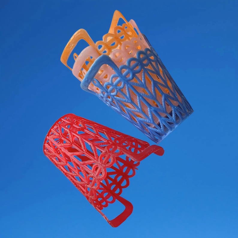 May include: Several colourful, open-weave, cylindrical containers with handles. The containers are in shades of red, blue, orange, and peach. The design features a repeating geometric pattern. The background is a solid, bright blue.