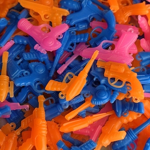 May include: A pile of colorful toy water guns in shades of blue, orange, and pink. The plastic guns vary in style, including pistols and rifles. The image is a close-up, showing the details of the toys.