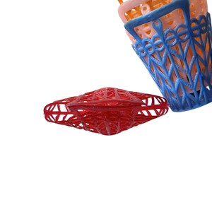 May include: A selection of colourful plastic baskets in red, blue, orange, and pink. The baskets feature a lattice design and handles. The red basket is flat, while the others are stacked.