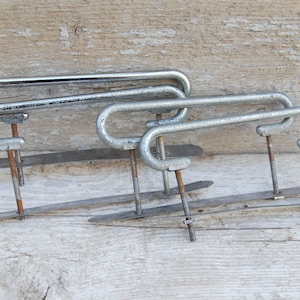 Op de afbeelding: Drie zilveren metalen ladegrepen met een gebogen ontwerp en een platte basis. De grepen zijn met schroeven aan de basis bevestigd.