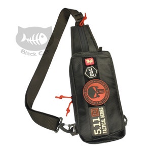 May include: Black tactical sling bag with red and white patches. The patches have text that reads "5.11 Tactical Series", "God Will Judge Our Enemies", "We'll Arrange The Meeting", and "EDC".