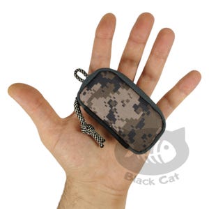 May include: A small camouflage-patterned pouch with a black zipper and a black and white cord.