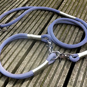 Puede incluir: Un juego de collar y correa para perro de cuerda a cuadros azules y blancos con detalles plateados. La correa tiene un clip de metal y el collar tiene un anillo de metal.