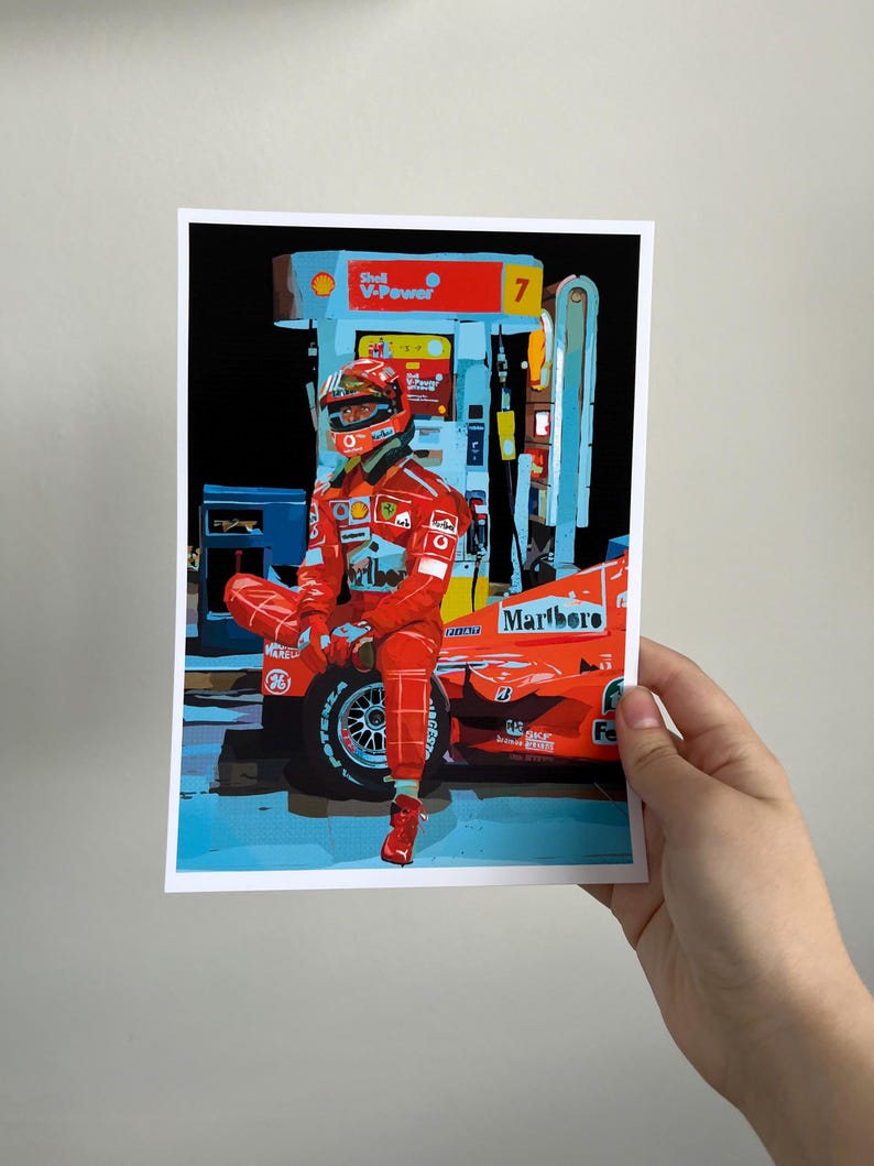 May include: A red race car with a driver wearing a red racing suit and helmet. The car is parked at a gas station with a Shell V-Power sign. The car has the word "Marlboro" on the side.
