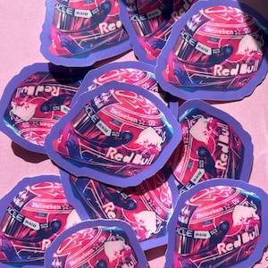 May include: A collection of stickers featuring a racing helmet design. The stickers have a purple border and a red, pink, and blue color scheme. The Red Bull logo and the word "Heineken" are visible on the helmet.