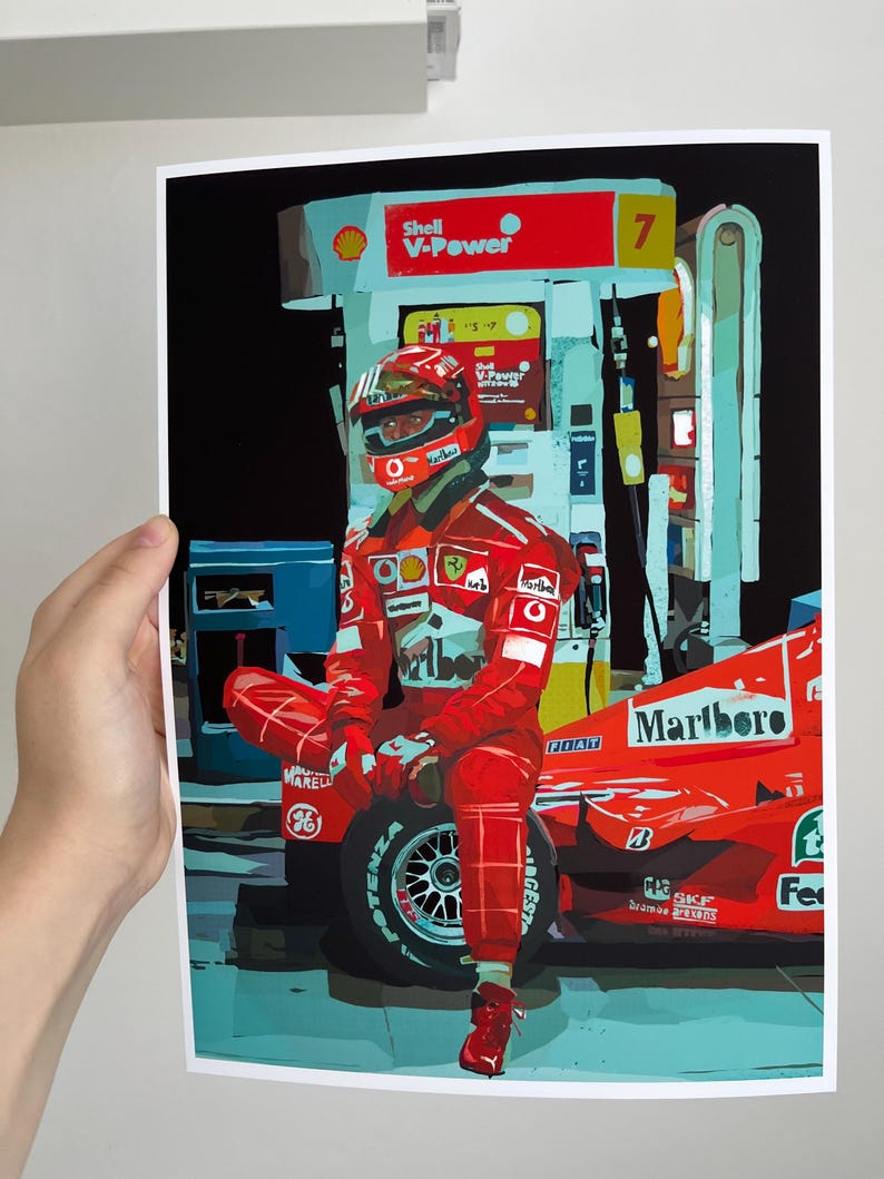 May include: A red Formula One race car with a driver wearing a red racing suit and helmet. The car is parked at a gas station with a Shell V-Power sign. The car has a Marlboro logo on the side.