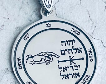May include: Silver pendant with a circular design featuring a hand pointing to a cross and Hebrew text. The pendant has a star of David at the top and a bail for attaching a chain.
