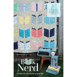 May include: A beige quilt with colorful book designs, measuring 54" x 66", is displayed. A vintage blue typewriter, a teacup, and a stack of books are on a small wooden table. The text "Bk Nerd" and "Perfect for the reader in your life!" are visible.