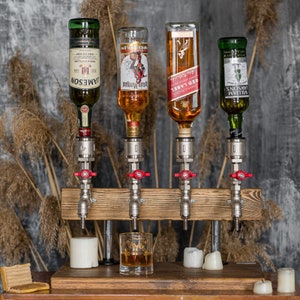 Alcohol dispenser for four bottles, made of brass plumbing pipes, silver-colored pipes, red-colored tap, on a wooden stand