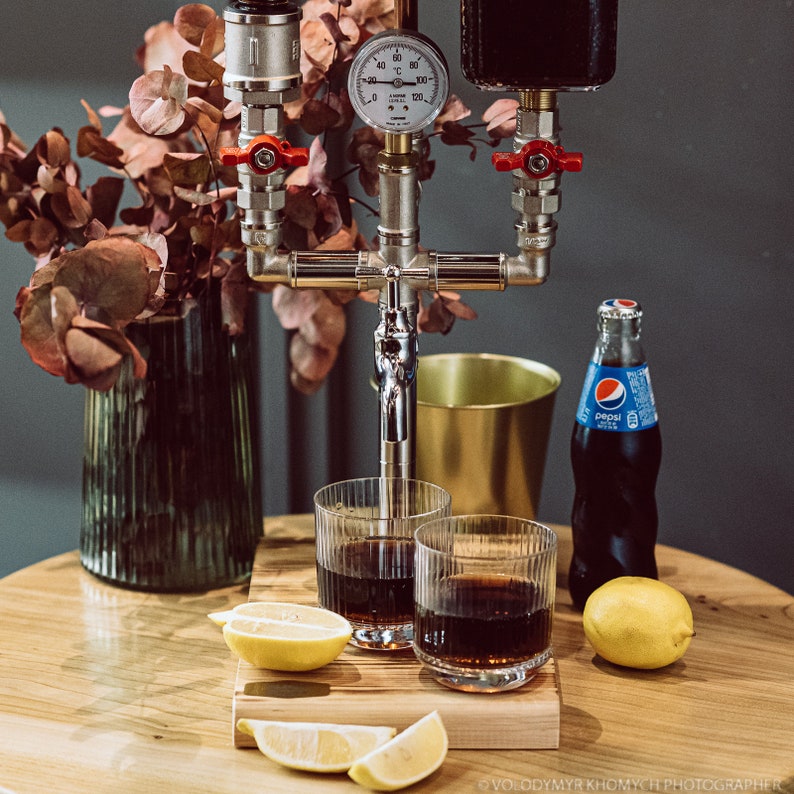 Dispenser for alcohol and non-alcoholic beverages for one bottle and beverage container with thermometer, made of brass plumbing pipes, on a wooden stand