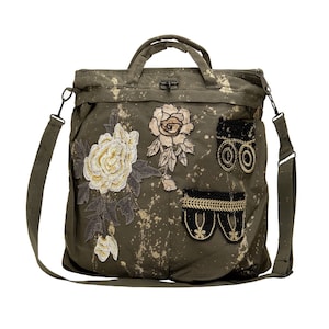 Peut inclure: Un sac cabas en toile verte avec une longue bandoulière. Le sac est éclaboussé de peinture dorée et décoré de fleurs brodées, d'un canon et d'une garniture noire et dorée.