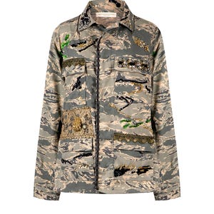 Può includere: Una giacca a stampa mimetica con chiusura a bottoni e maniche lunghe. La giacca è decorata con ricami e applicazioni dorate e nere, tra cui perline, paillettes e ricami.