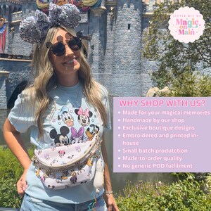 May include: A woman wearing a light blue t-shirt with a Disney character graphic, sunglasses, and a fanny pack. She is also wearing a pair of sequined mouse ears. The image includes the text "WHY SHOP WITH US?" and "Little Bit of Magic on Main."