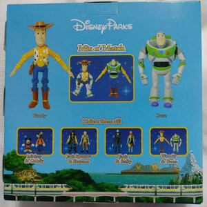 May include: A blue and white box with the text "Disney Parks Mix n' Match" on the front. The box features images of Woody and Buzz Lightyear from the Toy Story franchise. The back of the box shows different characters from Disney movies, including Mickey Mouse, Goofy, Jack Sparrow, and Jack Skellington.