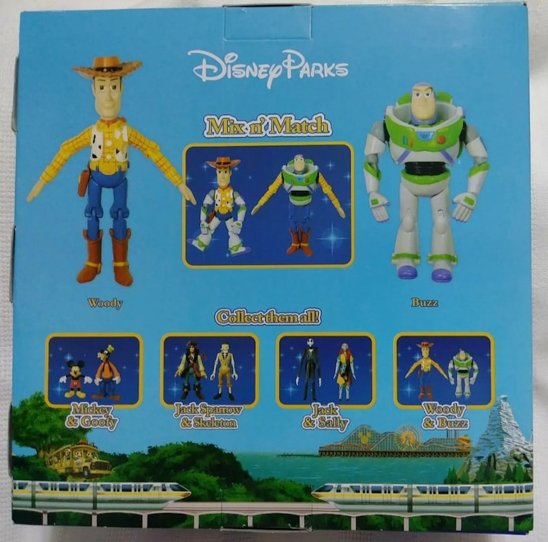 May include: A blue and white box with the text "Disney Parks Mix n' Match" on the front. The box features images of Woody and Buzz Lightyear from the Toy Story franchise. The back of the box shows different characters from Disney movies, including Mickey Mouse, Goofy, Jack Sparrow, and Jack Skellington.