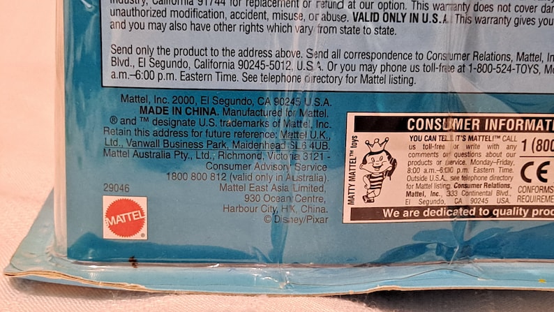 Pode incluir: Uma caixa de brinquedos de pl&aacute;stico azul e branca com uma imagem de um personagem de desenho animado na frente. A caixa tem as palavras "Matty Mattel" e "You Can Tell It's Mattel" impressas nela. A caixa tamb&eacute;m tem um r&oacute;tulo de informa&ccedil;&otilde;es para o consumidor com um n&uacute;mero de telefone gratuito e uma marca CE.