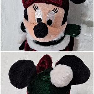 May include: A plush toy of Minnie Mouse dressed in a green and red Christmas outfit. She is wearing a red bow, a green hat with a white pom-pom, and a white fur trim around her neck.
