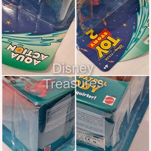 Pode incluir: Figura de a&ccedil;&atilde;o do Woody de Toy Story 2 em uma embalagem de pl&aacute;stico azul e verde. A figura est&aacute; segurando um esguicho de &aacute;gua. A embalagem tem as palavras 'Disney Pixar Toy Story 2' e 'Aqua Action' nela.