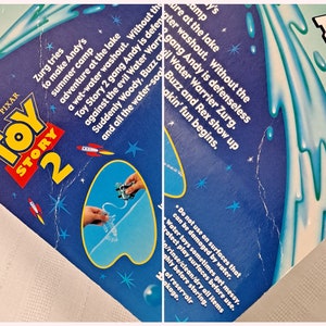 Peut inclure: Jeu d'eau Toy Story 2 avec Woody, Buzz l'&Eacute;clair et Rex. La bo&icirc;te bleue et blanche pr&eacute;sente une image des personnages jouant dans un cours d'eau bleu. Le texte sur la bo&icirc;te indique "Toy Story 2 Water Action".