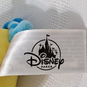 May include: A white tag with a black Disney Parks logo featuring a castle and the text "Disney Parks".