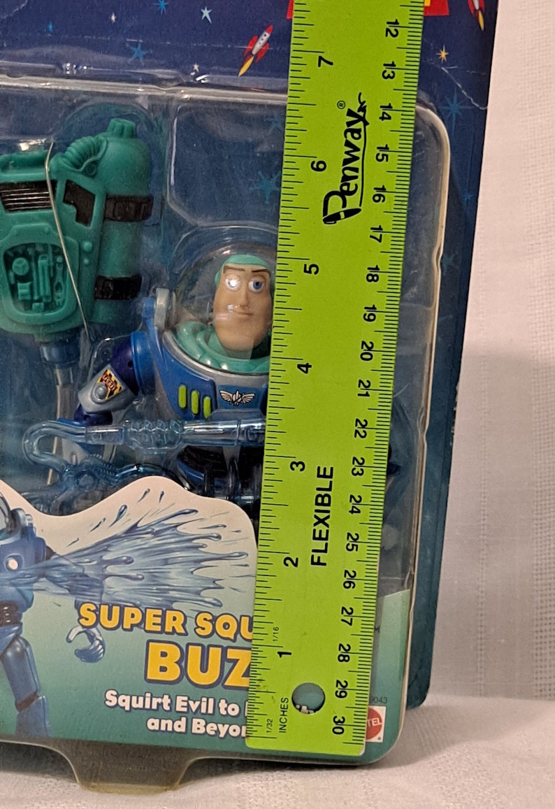 Peut inclure: Une figurine d'action en plastique bleu et vert de Buzz l'&Eacute;clair de la franchise Toy Story. La figurine tient un appareil qui projette de l'eau et se tient devant un fond bleu et blanc. L'emballage comprend le texte "Super Squirt Buzz" et "Squirt Evil to and Beyond".