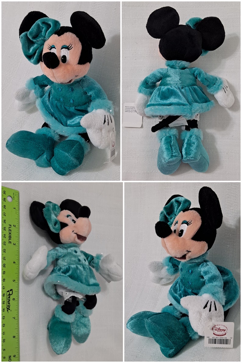 May include: A plush toy of Minnie Mouse wearing a teal blue dress with white fur trim and a matching teal blue bow. She is wearing white gloves and teal blue boots. The toy has a Disney Store tag attached to it.