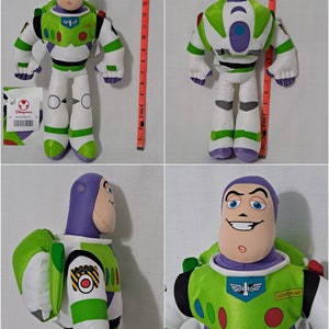Puede incluir: Un juguete de peluche Buzz Lightyear verde y blanco con detalles morados. El juguete tiene una cabeza grande con una cara sonriente y un parche negro en el ojo. El juguete lleva un traje espacial verde y blanco con un parche amarillo que dice "SPACE RANGER". El juguete est&aacute; de pie sobre una superficie blanca.