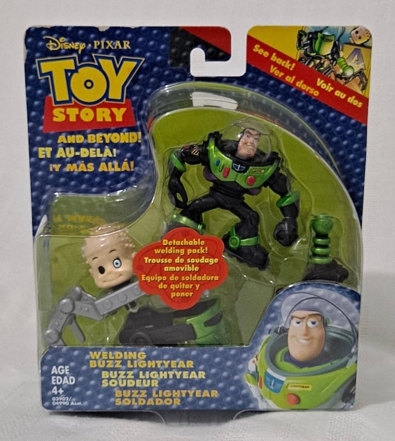 May include: Toy Story Buzz Lightyear action figure with a welding pack. The figure is green and black with a clear plastic helmet. The welding pack is green and silver. The packaging is red, blue, and yellow with the Toy Story logo and the words "And Beyond!" in English, French, and Spanish.