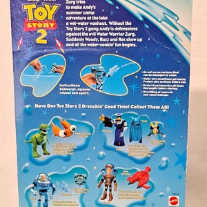 Peut inclure: Figurines Toy Story 2 Aqua Action, comprenant Woody, Buzz l'&Eacute;clair, Rex et Zurg. Les figurines sont activ&eacute;es par l'eau et pr&eacute;sentent un fond bleu et vert avec des &eacute;toiles. Le dos de l'emballage comprend des instructions d'utilisation et un avertissement concernant le remplissage excessif du r&eacute;servoir.