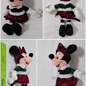 May include: A plush toy of Minnie Mouse dressed in a green and white Christmas outfit with a red velvet skirt and white fur trim. She is wearing a red velvet bow on her head and has a white fur trim around her neck.