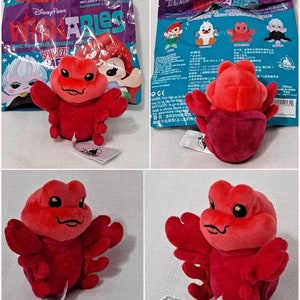 May include: Red plush toy of Sebastian the crab from Disney's The Little Mermaid. The toy is part of the Disney Parks Squish-A-bles collection. The toy is shown in a plastic bag with the Disney Parks logo and the words "Squish-A-bles" printed on it.