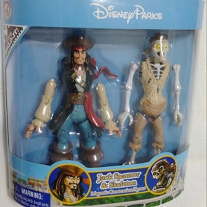 May include: A Disney Parks magnetic construction figure set featuring Jack Sparrow and Skeleton from the Pirates of the Caribbean franchise. The figures are packaged in a blue and white box with the Disney Parks logo.