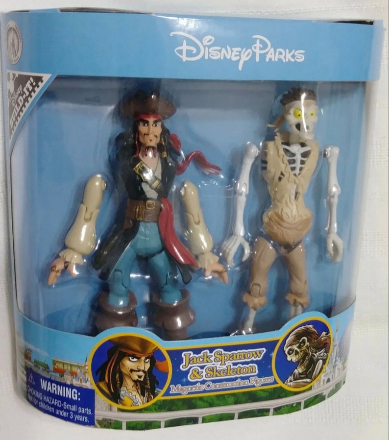 May include: A Disney Parks magnetic construction figure set featuring Jack Sparrow and Skeleton from the Pirates of the Caribbean franchise. The figures are packaged in a blue and white box with the Disney Parks logo.