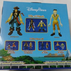 May include: A blue box with a picture of Jack Sparrow and the Skeleton from Pirates of the Caribbean. The box says "Disney Parks Mix 'n Match" and "Collect them all". There are smaller pictures of other Disney characters on the box, including Mickey Mouse and Goofy, Jack Sparrow and the Skeleton, Jack Skellington and Sally, and Woody and Buzz Lightyear.