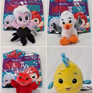May include: Four Disney Parks Wishables plush toys in their packaging. The toys are Ursula from The Little Mermaid, Scuttle from The Little Mermaid, Sebastian from The Little Mermaid, and Flounder from The Little Mermaid. Each plush toy is in a clear plastic bag with a colorful design featuring the Disney Parks logo and the Wishables name.