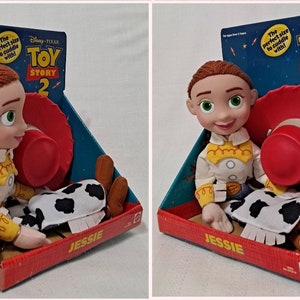 K&ouml;nnte beinhalten: Ein Pl&uuml;schtier von Jessie aus Toy Story 2, in ihrem charakteristischen Cowgirl-Outfit, mit einem roten Hut und braunen Stiefeln. Das Spielzeug ist in einer bunten Schachtel mit dem Toy Story 2-Logo verpackt.