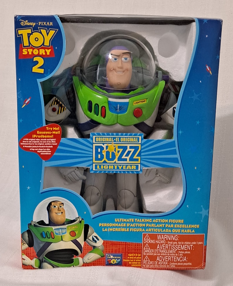 May include: A green and white Buzz Lightyear action figure from the Toy Story 2 movie. The figure is wearing a space ranger suit with a helmet and a red button that says "Lightyear". The figure is holding a laser gun. The box is blue and has a picture of Buzz Lightyear on it. The box says "Ultimate Talking Action Figure" and "Original - El Original Buzz Lightyear".