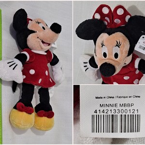 May include: A red and white polka dot Minnie Mouse plush toy with a black bow. The toy is approximately 25 cm tall and has a tag that says "Minnie MBBP" and "414213300121".