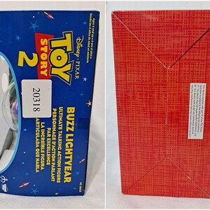 May include: Toy Story 2 Buzz Lightyear Ultimate Talking Action Figure box with a red, white, and blue design. The box features a picture of Buzz Lightyear in his spaceship. The box is labeled with the Toy Story 2 logo and the Disney Pixar logo.