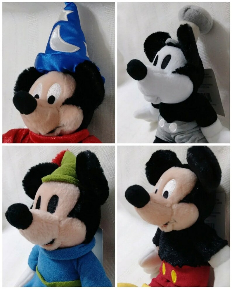 Op de afbeelding: Vier pluche Mickey Mouse-speelgoed in verschillende kostuums. De eerste draagt een blauwe tovenaarshoed met een halve maan, de tweede draagt een zwart-wit Steamboat Willie-kostuum, de derde draagt een groene Robin Hood-hoed en de vierde draagt een zwart-rood Sorcerer Mickey-kostuum.