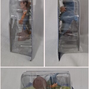 May include: A plastic package containing a toy figure of Woody from the Toy Story film franchise. Woody is wearing his signature cowboy hat and vest. The package is blue and yellow with the Toy Story logo.