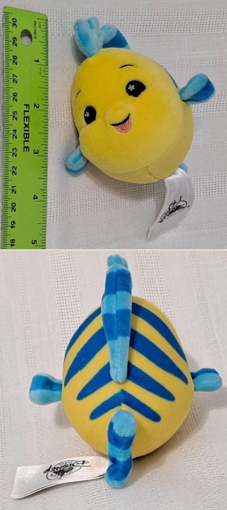 May include: Yellow and blue plush toy fish with a smiling face and a blue fin. The fish is about 5 inches long and has a white tag attached to it that says "Disney".