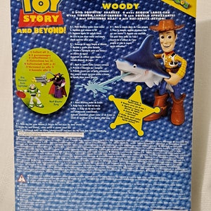 May include: Woody from Toy Story action figure holding a blue water squirting shark toy. The packaging features the Toy Story logo and the words "Adventures in Andy's Room".
