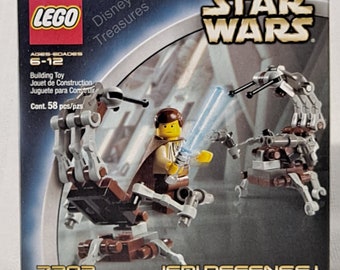 Può includere: Set di costruzione LEGO Star Wars Jedi Defense I con un droide marrone e grigio con una spada laser blu e una minifigure di Jedi. La scatola include il testo "LEGO Disney Treasures" e "STAR WARS".