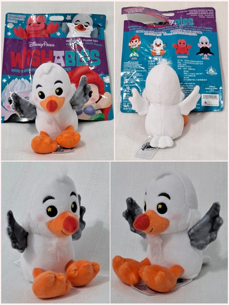 May include: A white plush toy seagull with orange feet and black wings. The seagull is sitting with its wings spread out. The toy is part of the Disney Pixar Wishables collection.